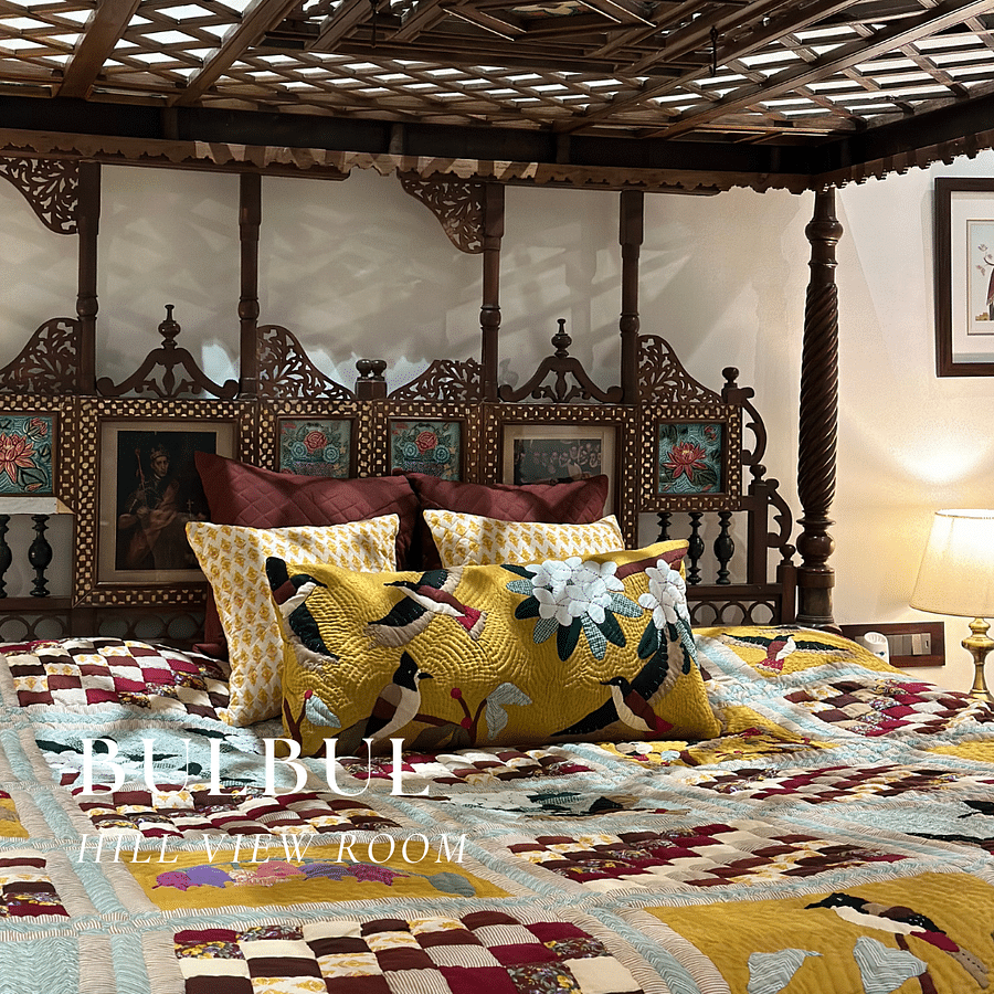 A bedroom with a four-poster bed and a colorful rug.